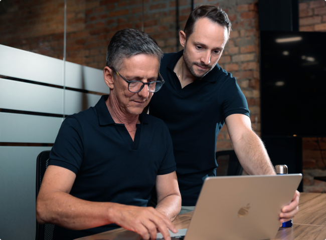 Imagem de dois homens olhando o computador focados no propósito do Grupo Vidalar